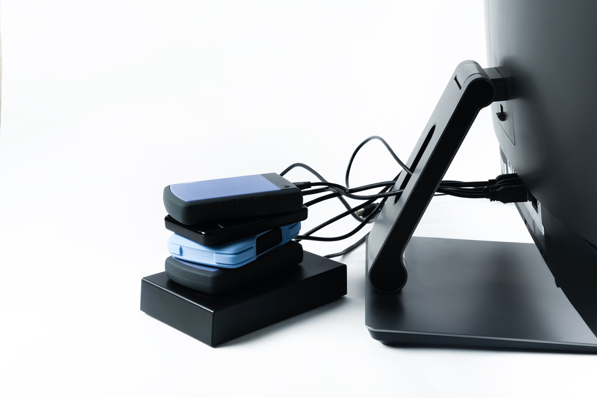 Multiple external hard drives connected to a monoblock on a white background.Computer with hard